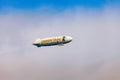 Blue dirigible flying in cloudy sky Royalty Free Stock Photo