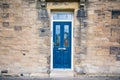 Blue door building with traditional silver handles and glass windows in stone build house