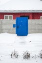 Blue door and concrete fence during a snowfall in winter Royalty Free Stock Photo