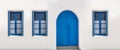 Blue door and three windows with open shutters on white wall. Greek island house front view Royalty Free Stock Photo