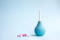 Blue douche and tablets of pink and white color on a blue background. Medical concept