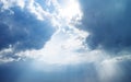 Blue dramatic sky background with clouds and sun rays coming out. Royalty Free Stock Photo