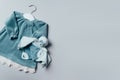 Blue dress for baby girl, soft toy with white hanger on grey background. Set of baby clothes and accessories for Royalty Free Stock Photo