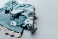 Blue dress for baby girl, soft toy with white hanger on grey background. Set of baby clothes and accessories for Royalty Free Stock Photo