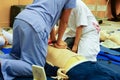 A blue dress trainee nurse performing chest compression on a man