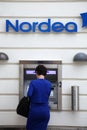 Blue dressed woman make a withdravel from Nordea cash point