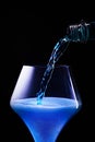 Blue drink is poured into a glass.