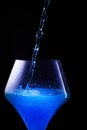 Blue drink is poured into a glass