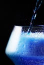 Blue drink is poured into a glass