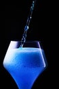 Blue drink is poured into a glass. Refreshing drinks.