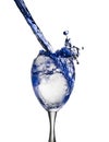 A blue drink is poured into wine glass causing a splash, isolated on white background Royalty Free Stock Photo