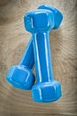 Blue dumb-bells on wooden board top view fitness concept
