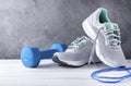 1 blue dumbbell, skipping rope, gray sneakers on a gray