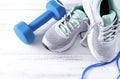 1 blue dumbbell, skipping rope, gray sneakers on a gray top view