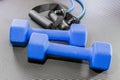 Blue dumbbell weights and resistance bands lying on a black yoga