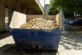 Blue dumpster with broken bricks and plaster after apartment repair on a sunny summer day. Large container with construction Royalty Free Stock Photo