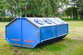 Blue dumpster for municipal waste or industrial waste, on green grass