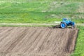 Blue dusty tractor with seedbed cultivator standing at the edge Royalty Free Stock Photo