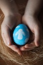 blue easter egg with painted angel in hands Royalty Free Stock Photo
