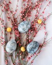 Blue easter eggs with small golden chocolates on pink flower background.