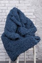 Blue eco fur coat, faux fur, thrown on a chair, against a brick wall