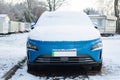 Blue electric car with green numberplate stripe with snow on the bonnet