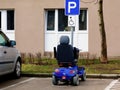 Blue electric disability or handicap scooter in handicap parking stall.