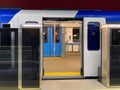 A blue electric train carriage with an open sliding mechanical door at a train station platform Royalty Free Stock Photo