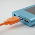 A blue electronic device with a rectangular design is connected to an orange USB Royalty Free Stock Photo