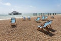Blue empty deckchairs on the beach. The old pier in Brighton in Royalty Free Stock Photo