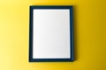 Blue empty picture frame on yellow wall background Royalty Free Stock Photo