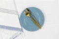 Blue empty plate with fork, knife, white striped textile napkins on wooden table. Golden cutlery, table setting utensils Royalty Free Stock Photo