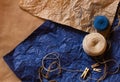 Blue end beige skein of thread, tiny pins on natural brown and blue crumpled blue paper. Design templates with free copy space for Royalty Free Stock Photo