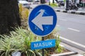 Blue enter sign with a white arrow pointing to the left on blue background next to a road