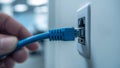 Blue Ethernet Cable Plugging into Wall Socket Royalty Free Stock Photo