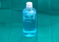 Blue ethyl alcohol liquid in plastic transparent bottle on green