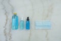 Blue Ethyl Alcohol spray bottle, Alcohol gel bottle, Alcohol in plastic bottle and blue surgical masks on the marble desk.