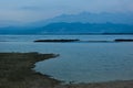 Blue evening on sea beach with mountains in fog on horizon in calm cloudy sunset. Overcast landscape on indonesian island, travel. Royalty Free Stock Photo