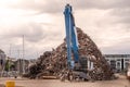 Blue excavator with claw arm in a scrap metal yard. Metal recycling industry. Export of junk for profit and ecology. Port area Royalty Free Stock Photo