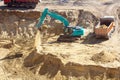 Blue excavator at a construction site working on a pile of sand. The tractor loads the earth into the car. Construction scene top