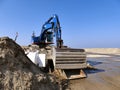 Blue excavator on pile of sand on construction site Royalty Free Stock Photo