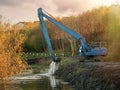 Blue excavator working on a river,