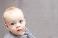 Blue-eyed baby boy looking at camera with reproach. Open-eyed cute infant kid. Copy space Royalty Free Stock Photo