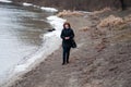 Blue-eyed beautiful woman with red curly hair walks on river in winter or late autumn Royalty Free Stock Photo