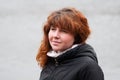 Blue-eyed beautiful woman with red curly hair walks on river in winter or late autumn Royalty Free Stock Photo