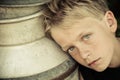 Blue eyed boy leans head against metal container