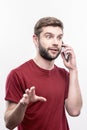 Blue-eyed businessman feeling surprised while calling his business partner