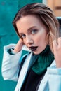 Blue-eyed fashion model with dark lipstick posing outside