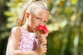 Blue eyed girl smelling flower outdoors. Royalty Free Stock Photo