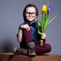 A blue - eyed kid with glasses.A boy sits with a smile on face.